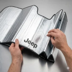 A person easily folding a compact windshield sun shade jeep wrangler for convenient interior storage.